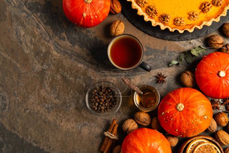 thanksgiving theme, homemade pumpkin pie near gourds, warm tea and aromatic honey on stone table