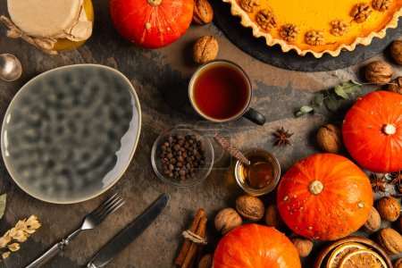 thanksgiving setting with ceramic plate, ripe gourds and pumpkin pie near autumnal festive objects
