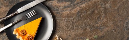 assiette en céramique noire avec tarte à la citrouille thanksgiving et couverts vintage sur table en pierre, bannière