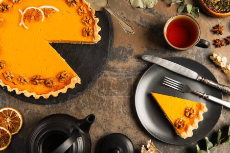 colorful thanksgiving setting, pumpkin pie near black tableware and vintage cutlery on stone surface