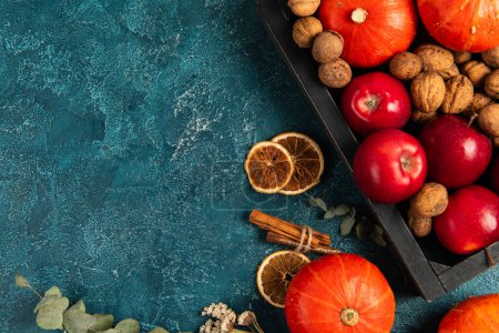 Photo for Thanksgiving backdrop, tray with fall harvest near orange slices and herbs on blue textured surface - Royalty Free Image