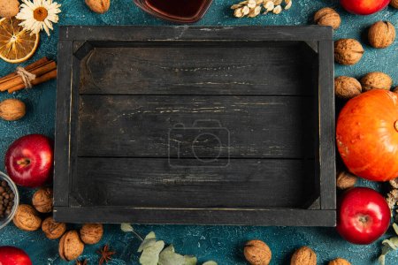 wooden tray surrounded with colorful objects of fall harvest on blue textured surface, thanksgiving