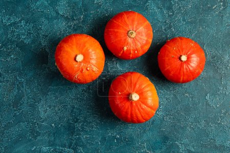 colorful thanksgiving backdrop with fresh ripe orange pumpkins on blue textured tabletop, top view