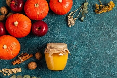 Téléchargez les photos : Thanksgiving toile de fond, citrouilles près du pot de miel et les objets de récolte d'automne sur la surface texturée bleue - en image libre de droit
