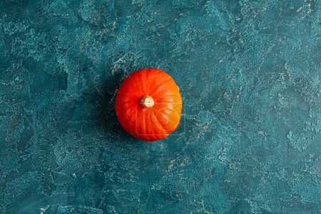 Téléchargez les photos : Thanksgiving toile de fond, une citrouille orange vif sur fond texturé bleu, perspective de haut en bas - en image libre de droit