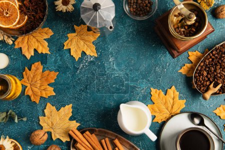 café y leche sobre mesa de textura azul con follaje dorado y decoración otoñal, telón de fondo de acción de gracias