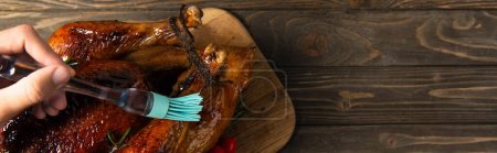 hombre cortado engrase pavo asado con cepillo de silicona, preparación de la cena de acción de gracias, pancarta