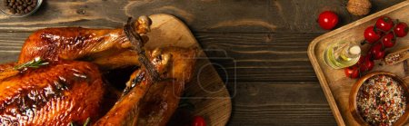 thanksgiving meal, roasted turkey near red cherry tomatoes and spices on rustic wooden table, banner