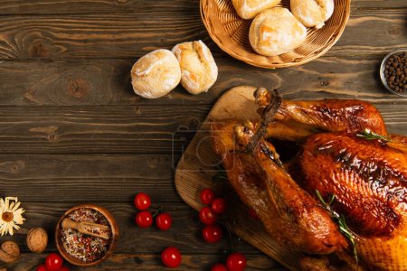 Photo for Wooden table with grilled turkey and buns near spices and cherry tomatoes, delicious thanksgiving - Royalty Free Image