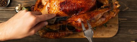 Téléchargez les photos : Vue rapprochée de l'homme cultivé coupant délicieuse dinde rôtie pour le dîner de thanksgiving, bannière - en image libre de droit