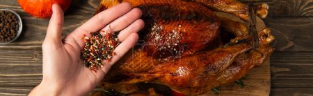 Photo for Delicious thanksgiving dinner, cropped view of man holding spices near grilled turkey, banner - Royalty Free Image