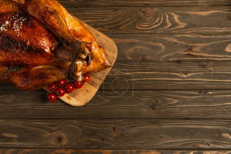 thanksgiving still life, roasted turkey on cutting board near cherry tomatoes on rustic wooden table