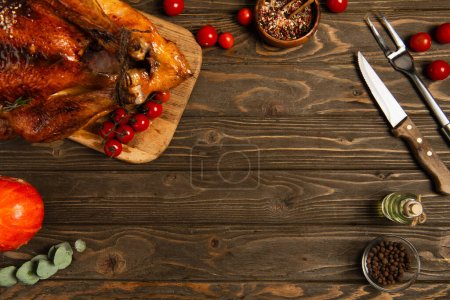 Photo for Thanksgiving backdrop, roasted turkey with spices and red cherry tomatoes on textured wooden surface - Royalty Free Image