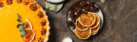 pastel de calabaza de acción de gracias cerca de rebanadas de naranja seca y especias aromáticas en la mesa de piedra, pancarta