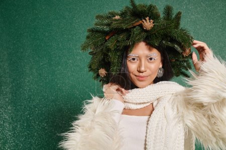 Téléchargez les photos : Heure d'hiver, femme gaie avec maquillage blanc et tenue tendance ajustant la couronne sous la neige tombante - en image libre de droit