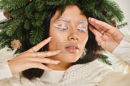 Photo for Winter beauty, close up of charming woman with closed eyes wearing green wreath and touching face - Royalty Free Image