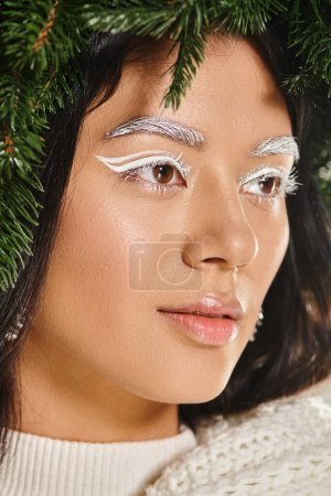 Winterschönheit, Nahaufnahme einer attraktiven asiatischen Frau mit weißem Augen-Make-up und Lippenbalsam, die wegschaut
