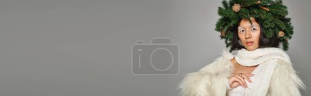 banner of winter queen with white eye makeup and beads on face posing in wreath on grey background