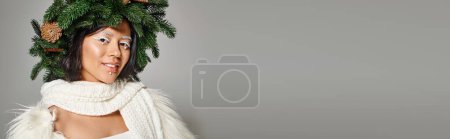 Photo for Happy asian woman with white eye makeup and beads on face posing in wreath on grey backdrop, banner - Royalty Free Image