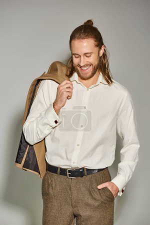 Photo for Positive and bearded businessman in white shirt posing with beige blazer on shoulder on grey - Royalty Free Image