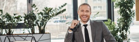Photo for Portrait of successful elegant businessman in grey suit smiling at camera in modern office, banner - Royalty Free Image