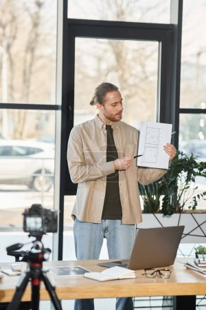 creative manager in casual attire showing blue print during video presentation in modern office