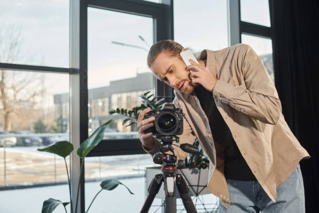 businessman talking on smartphone near professional digital camera in office, video blogger