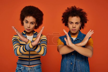 african american brother and sister showing denial gesture looking at camera, family concept