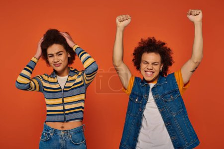 Photo for One young african american sibling looking negatively while other very cheerful, family concept - Royalty Free Image