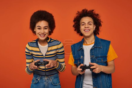 good looking african american brother and sister playing video games with joysticks, family concept