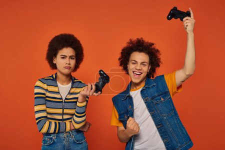 young african american brother and sister playing video games with joysticks, family concept