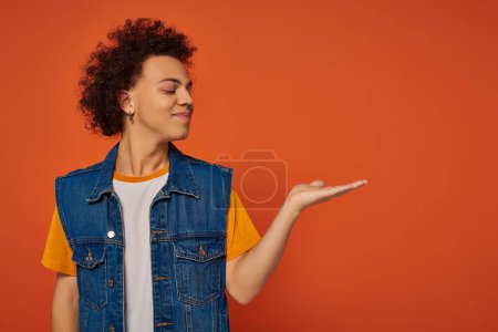 handsome african american male model in casual urban attire posing actively on orange background