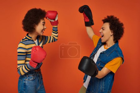 happy african american siblings in boxing gloves having fun together on orange backdrop, family