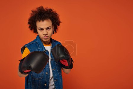 good looking sporty african american man posing lively in boxing gloves on orange background