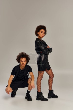 attractive stylish african american siblings in fashionable black outfits posing lively together