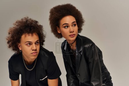 Porträt junger afrikanisch-amerikanischer Geschwister in modischer schwarzer Kleidung, die vor grauem Hintergrund posieren
