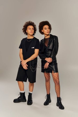 attractive stylish african american siblings in fashionable black outfits posing actively together