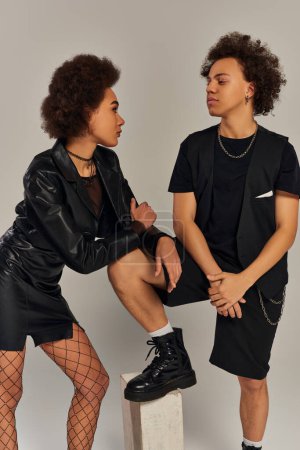 fashionable african american siblings in black urban outfit posing together on gray backdrop