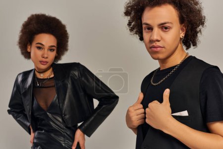 trendy young african american brother and sister in urban clothes posing together on gray backdrop