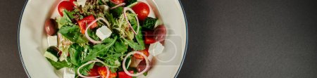 photo de vue du dessus de l'assiette avec une délicieuse salade grecque fraîchement préparée sur fond gris, bannière