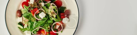photo de vue du dessus de l'assiette avec salade grecque traditionnelle fraîchement préparée sur fond gris, bannière alimentaire