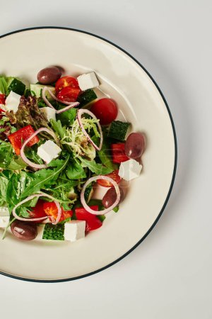 Foto de Foto vertical del plato con ensalada griega recién hecha sobre fondo gris, alimentación saludable - Imagen libre de derechos