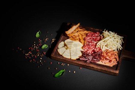vista en ángulo alto del tablero de charcutería con selección de queso gourmet, carne seca y rebanadas de salami