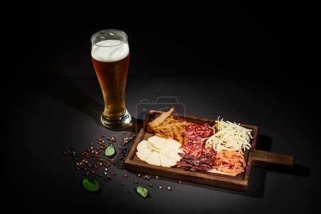 szklanka zimnego piwa w pobliżu Charcuterie pokładzie z serem dla smakoszy, suszona wołowina i salami na czarno