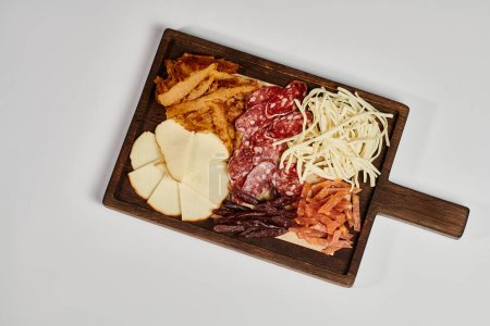 Photo for Charcuterie board with gourmet cheese platter, dried beef and salami slices on grey backdrop - Royalty Free Image