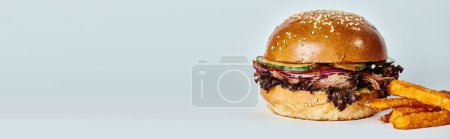 pancarta de sabrosa hamburguesa con carne de res, cebolla roja, tomate y pan de sésamo cerca de papas fritas en gris