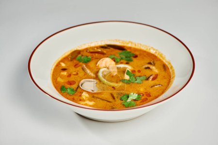 soupe thaïlandaise savoureuse au lait de coco, crevettes, citronnelle et coriandre sur fond gris, Tom yum