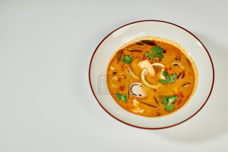 Téléchargez les photos : Soupe thaïlandaise crémeuse au lait de coco, crevettes, citronnelle et coriandre sur fond gris, Tom yum - en image libre de droit