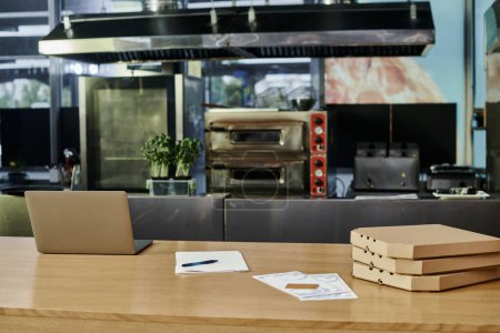 laptop w pobliżu pudełek po pizzy i karty menu na drewnianym blacie w nowoczesnej kawiarni, przytulna atmosfera