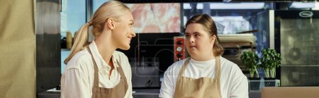 Foto de Administrador positivo hablando con una joven empleada con síndrome de Down en la cafetería moderna, pancarta - Imagen libre de derechos